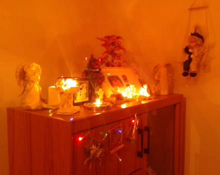 Gedenkschrank mit Harlekin auf Schaukel. Weihnachtszeit mit Teelichtern und bunter LED Lichterkette